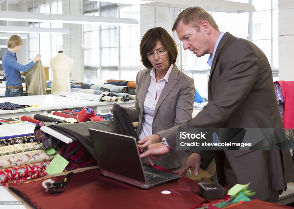 Textile Business A businesswoman and businessman entering textile inventory into a laptop and he is pointing out to her a detail. 20-29 Years Stock Photo