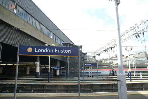 View of hall of Waterloo train station, terminal station for trains to South-West London and South England. Modern glass building. Lots of passengers inside of hall. Public transportation