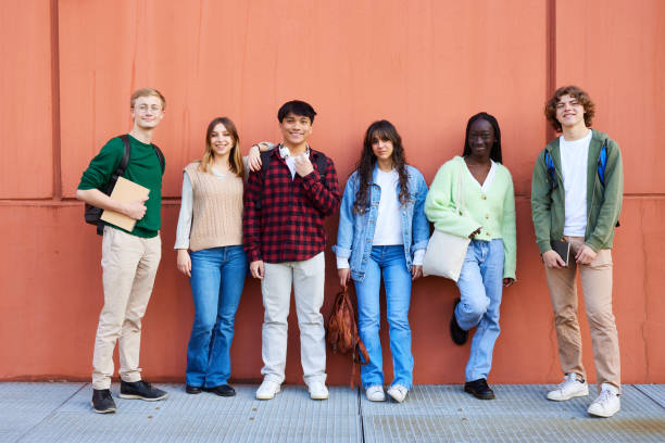 istock Happy friends standing against red wall at campus 1734965036