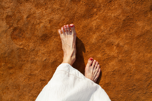 A woman walking barefoot on ochre ground. Close-up of foot. Concept of the process of connecting with the earth's energy. Top view.