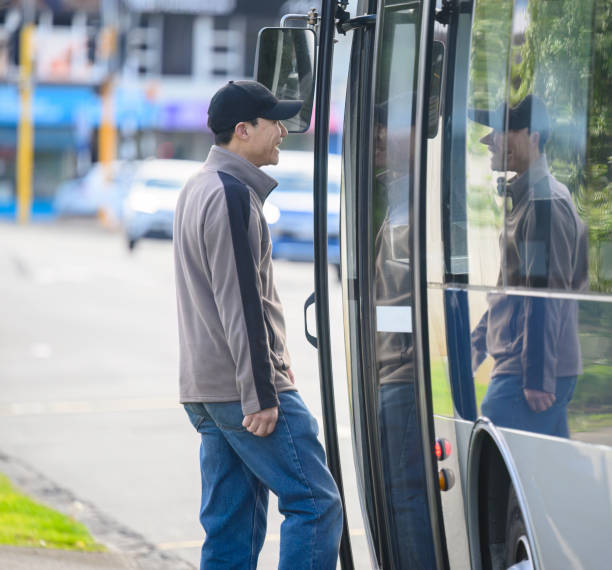 Man smiling and walking into the bus at bus stop. Auckland. Vertical format.
