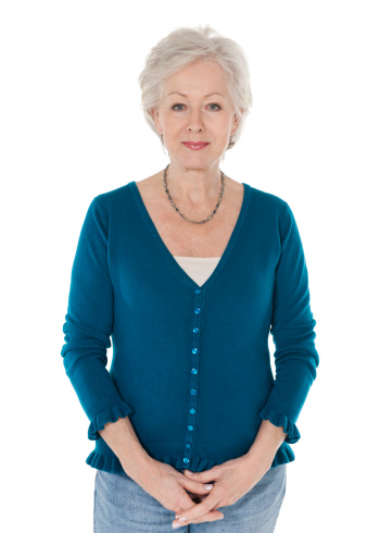 Portrait of confident senior woman standing hands clasped over white background.