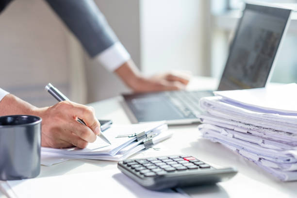 オフィスでノートパソコンと書類を机の上に置いたビジネスマン、 - 書類 ストックフォトと画像