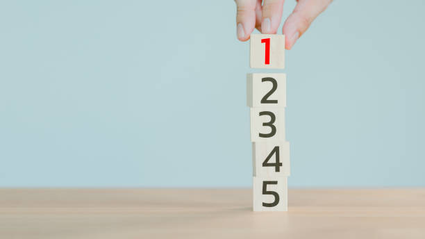 Hand putting a wooden cube with number 1 on wood cube stack alphabet 2 3 4 5 on wood table. Arrange to do list, Task priority, management and business important planning concept.
