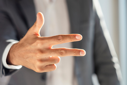 unrecognizable businessman in suit making three fingers sign