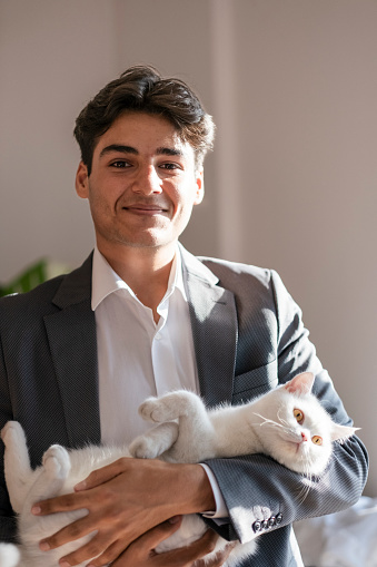 handsome young man loving his cat on his lap