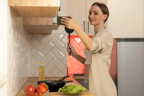 Photo of Female food blogger cooks food and records videos on a smartphone
