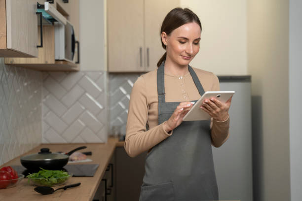 istock A woman in an apron is standing at home in the kitchen using a digital tablet 1735017926