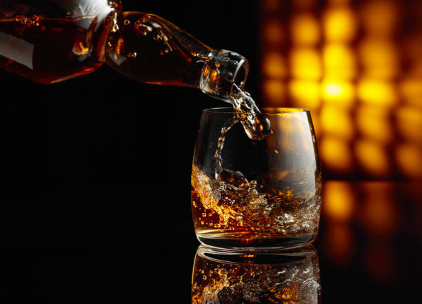 pouring whiskey from a bottle into a glass. - action alcohol alcoholism bar imagens e fotografias de stock