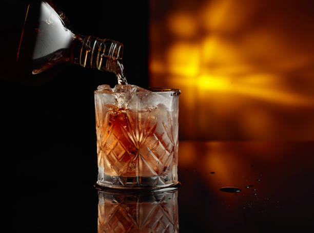 istock Pouring whiskey from a bottle into a glass with ice. 1735033676