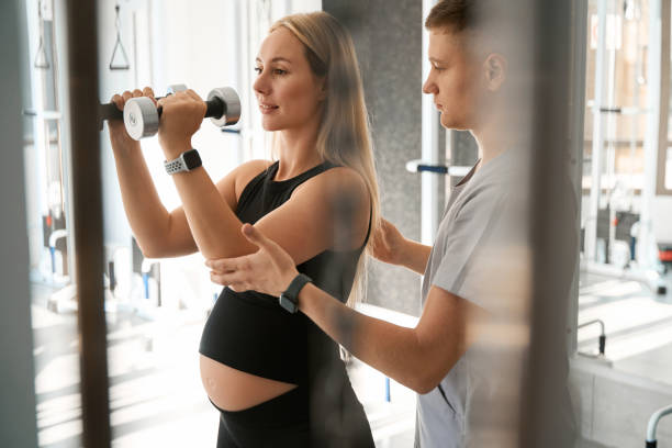 istock Pregnant woman performs exercises with dumbbells with physiotherapist 1735033763