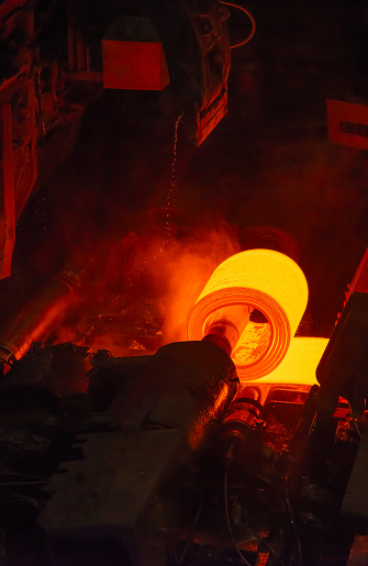 Hot steel slab passes along a rolling machine at a steel plant.