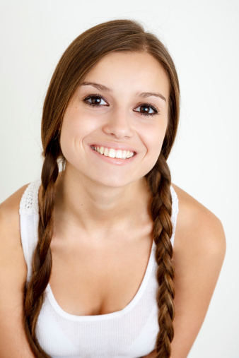 smiling girl with braids looking at camera on white background