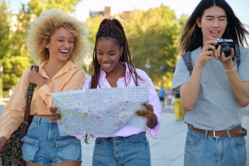 Three multiracial friends sightseeing with a local map and a camera in Madrid, Spain.