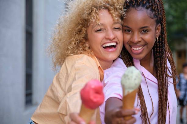 istock Two multiracial happy friends with ice creams smiling in summer. 1735046443