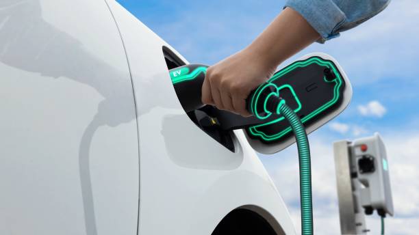 istock Hand insert smart EV charger to electric car with sky and cloudscape. peruse 1735053384