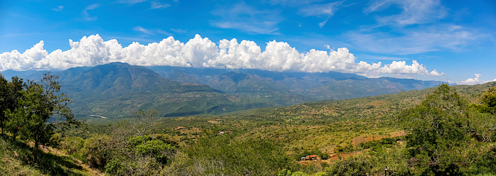 Panorama of wonderful view from Barichara, Colombia over green landscape to mountains with blue sky and white clouds along the mountain ridge