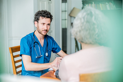 Doctor talking to senior woman patient at house