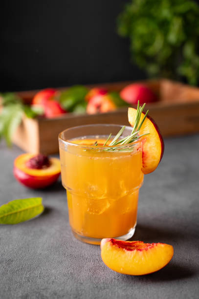 thé aux pêches avec glace et romarin sur un verre. boisson saine végétalienne faite maison sur un fond sombre avec des fruits frais. - georgia peach photos et images de collection