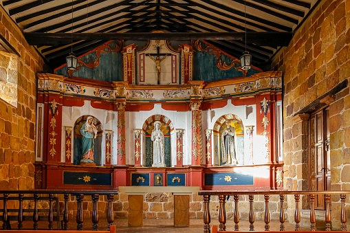Interior of Santa Barbara Chapel with statues, paintings and stone walls, Barichara, Colombia