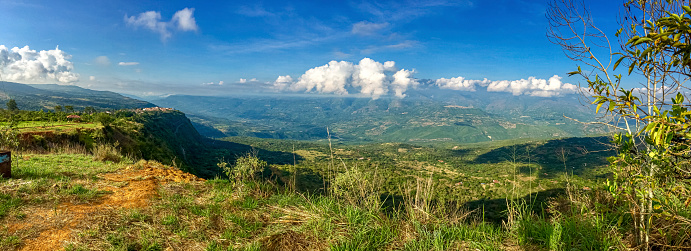 Panorama over the cliffs into a green valley and mountains in sun and shadow, blue sky and white clouds Barichara, Colombia