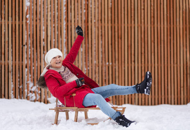 istock Senior woman having fun during cold winter day, sledding down the hill. 1735146524