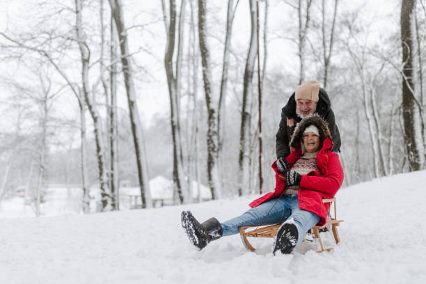 istock Senior couple having fun during cold winter day, sledding down the hill. 1735147053