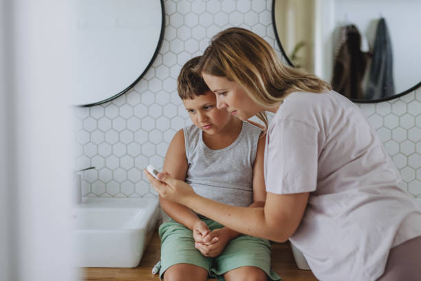 自宅で指先血糖計を使って息子の血糖値をチェックする母親。 - hypoglycemia diabetes child hyperglycemia ストックフォ��トと画像