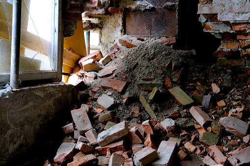 ruined room in abandoned building with broken windows without glass, basement air raid shelter, pile of bricks lying around, concept of destruction of buildings from bombing and rocket attacks