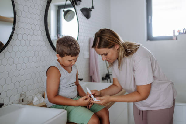 自宅で指先血糖計を使って息子の血糖値をチェックする母親。 - hypoglycemia diabetes child hyperglycemia ストックフォトと画像