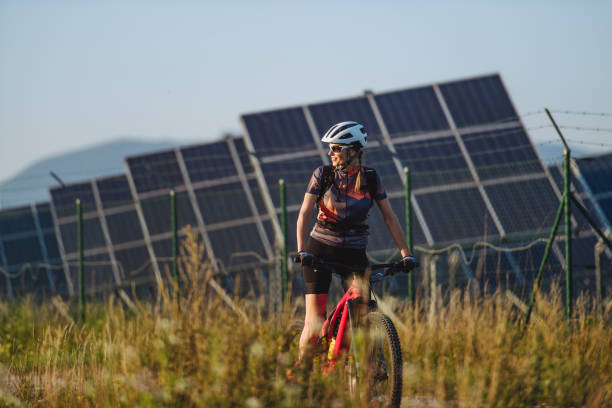 istock Beautiful cyclist riding in front of solar panels at a solar farm. 1735170949