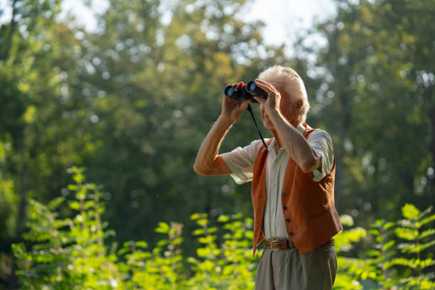 istock Senior man spending free time outdoors in nature, watching forest animals through binoculars. 1735182538