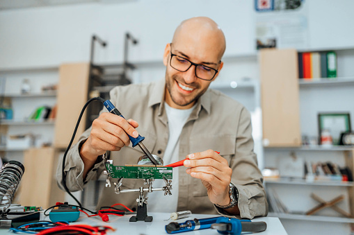 Young smiling man repairing electrical components of a computer