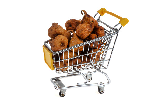 Supermarket trolley of dried figs close-up on white background