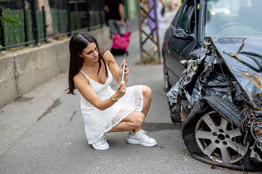The young woman, equipped with a digital tablet, takes photos of the car's damage, ensuring a meticulous record of the accident's consequences