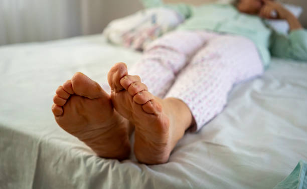 old women feets are foreground she is in bed horizontal still