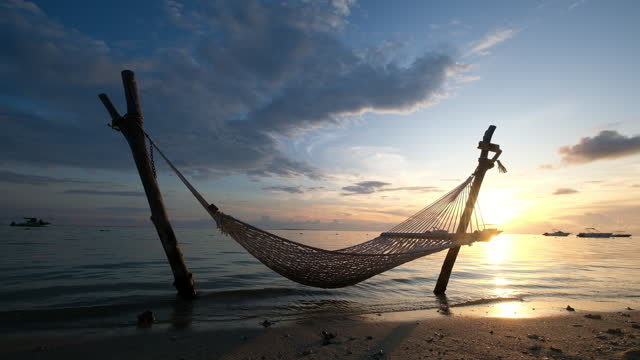 Wide angle video shot of a hammock net installed on the shallow sandy beach on Le Morne peninsula, Mauritius. Calm sunset time 4k footage.