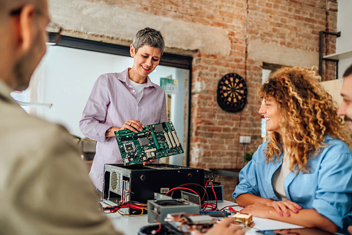 Electronics professor teaching a group of students about computer parts