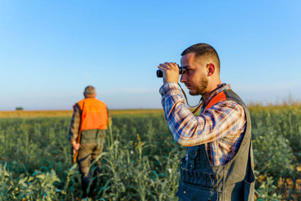 istock Young male hunter looking through binoculars, while his mature father is walking in the field 1735232453