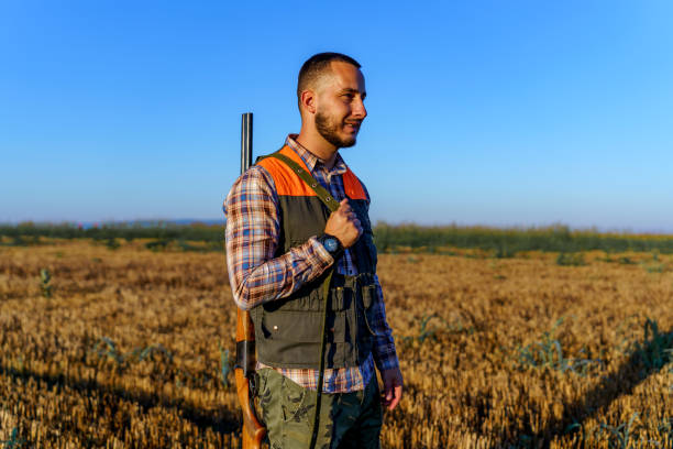 istock Young male hunter carrying a rifle on his shoulder, while standing in a wheat field 1735232986