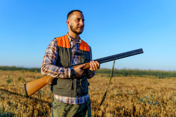 istock Young male hunter standing in a field, while holding a rifle in his hands 1735232995