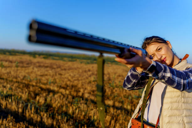 istock Young female hunter standing in nature on a sunny day, while holding a rifle with both hands and aiming it at her prey 1735233519