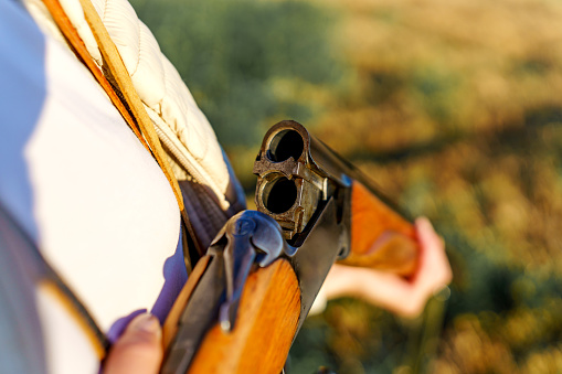 Close-up of a young Caucasian female hunter`s hand holding a shotgun open and checking her bullets.