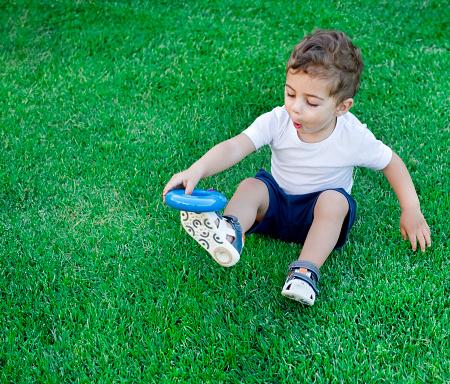 baby boy playing on the garden grass with a blue hoop