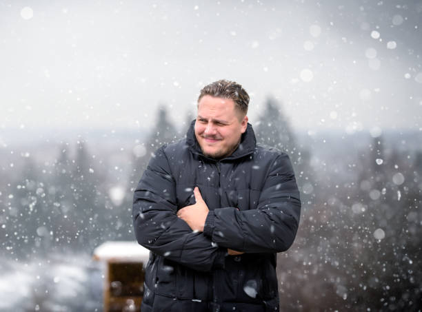 Young man in a thick winter jacket looking critically to the side