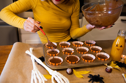 Young woman preparing chocolate muffins for Halloween