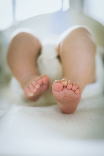 Close up of cute baby feet on white bed, shallow depth of field