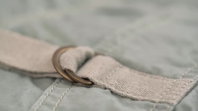 two metal half-rings on the canvas belt of the khaki trousers pocket. closeup rotation.