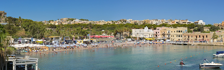 St Julians, Malta - 3 August 2023: Panoramic view of the seafront and beach of St George's Bay in the town of St Julians