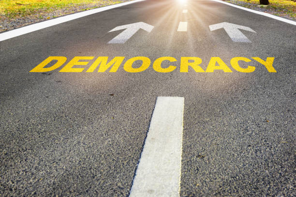 istock Democracy written on road with white arrow on asphalt road 1735336535